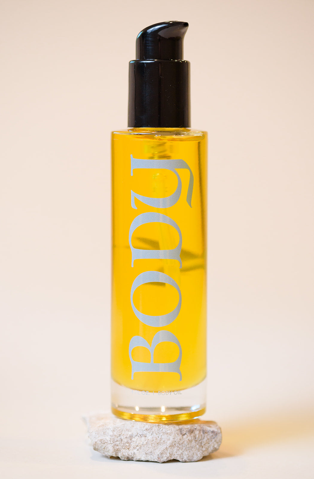 A bottle of body oil with a black cap, formulated to hydrate and nourish skin, featuring a blend of natural oils and soothing scents.